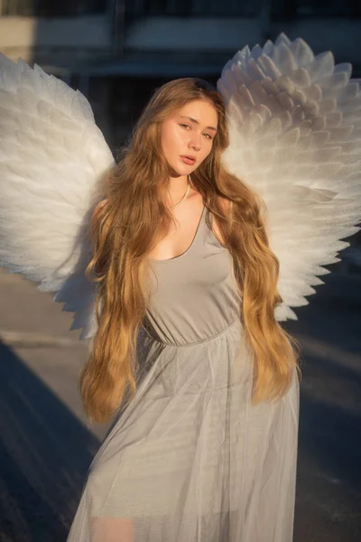 長いブロンドの髪の美しい女の子 大きな翼を持つ天使の少女が太陽の前に立っている 天使の上の太陽光線 — ストック写真