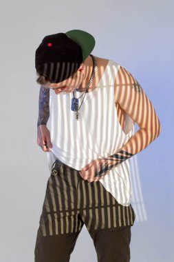 Genç, yırtık pırtık bir rapçinin portresi stüdyoda beyaz arka planda, orijinal sanat ışığı altında..