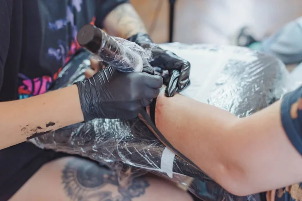 Kuaförde dövmenin kesilip atılmış hali. Dövmeci, dövme makinesinin iğnesini kullanarak cilde mürekkep enjekte ediyor. Stüdyoda çalışan profesyonel bir dövmeci. Seçici odak