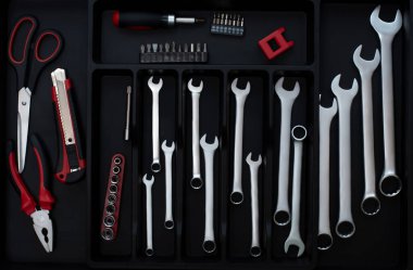 Siyah bir organizatöre katlanmış büyük kırmızı siyah ve metalik el aletleri koleksiyonu. Birçok araçlı plastik siyah kap.