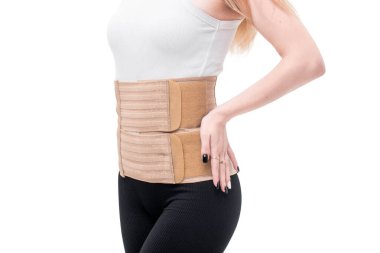 Bel destek kemeri takan bir kadın. Beyaz arka planda geçirilen ameliyattan sonra hamile ve doğum sonrası bel desteği..