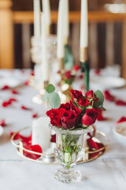 Romantik bir akşam yemeği masası kırmızı güller, vazolar ve mumlarla süslenir..