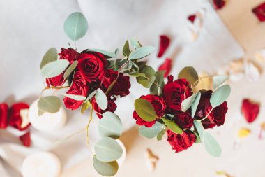 Romantik bir akşam yemeği için dekor. Kırmızı güller, yapraklar ve mum.