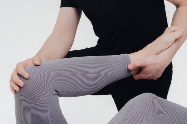 Fizyoterapist bacak yaralanmasını tedavi eder ve hastanın alt uzuv egzersizlerini beyaz arka planda yapmasına yardım eder..