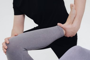 Fizyoterapist bacak yaralanmasını tedavi eder ve hastanın alt uzuv egzersizlerini beyaz arka planda yapmasına yardım eder..