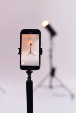 Tripodun üzerindeki bir akıllı telefon, sakin bir ortamda sanatsal ve yenilikçi teknikler sergileyen çağdaş bir stüdyoda bir ışık ayarı yakalar..
