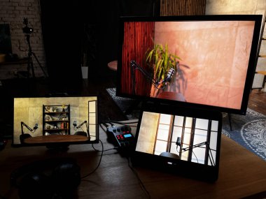 Multiple screens show various angles of a podcast recording setup. The room has a warm ambiance with plants and a wooden table, creating an inviting atmosphere for discussions. clipart