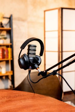 İyi organize edilmiş bir podcast seansları profesyonel mikrofonlar ve bir masanın üzerine yerleştirilmiş kulaklıklar içerir. Stüdyo rahat bir atmosfer yayar, yaratıcılık için mükemmeldir..