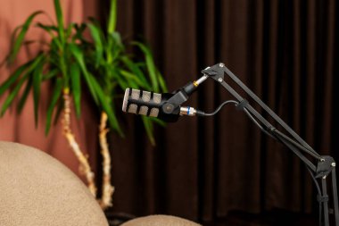 İyi donanımlı bir röportaj alanında, ayarlanabilir bir kola monte edilmiş bir mikrofon, yakında rahat bir sandalye, kapalı tesisler ve yumuşak ışıklandırmalarla çevrili.