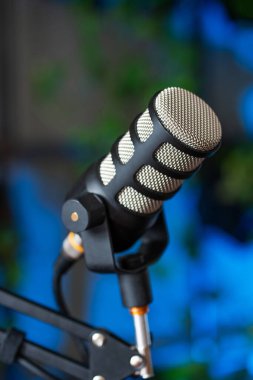 Röportajlar için podcast kaydı için hazır şık bir mikrofon. Ayar canlı, bulanık arka plan ışıkları içeriyor, canlı tartışmalar için çekici bir atmosfer yaratıyor..