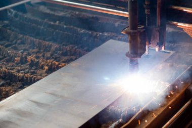 Endüstriyel atölye içindeki metal bir levhaya odaklanan hassas plazma kesimi devam ediyor.