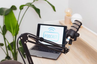 İyi organize edilmiş bir çalışma alanı podcast kaydı için hazırlanır. Podcast arayüzü gösteren bir dizüstü bilgisayarın yanına yerleştirilmiş bir mikrofon, bilgilendirici röportajlar için ideal bir ayar oluşturur.