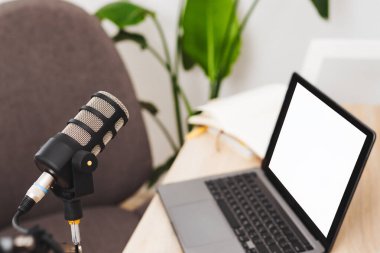 Modern ofis alanındaki boş bir dizüstü bilgisayarın yanına bir mikrofon yerleştirilir. Ayarlar, eğitim ve derslere odaklı yaklaşan bir podcast öneriyor.