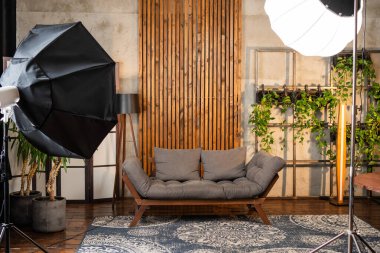 İyi tasarlanmış bir podcast stüdyosunda rahat bir kanepe, stüdyo ışıkları ve mikrofon bulunmakta olup röportaj ve sohbet için davetkar bir ortam yaratmaktadır..