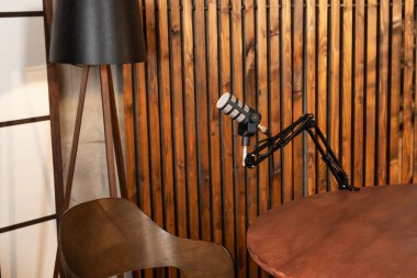 İyi düzenlenmiş bir podcast seti, ayarlanabilir bir kola monte edilmiş bir mikrofon, ahşap bir masa ve şık bir sandalye, mülakat yapmak için mükemmel..