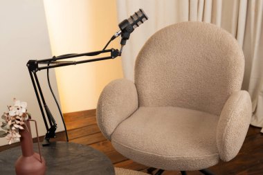 Rahat bir sandalye, podcast röportajları için tasarlanmış esnek bir kola monte edilmiş bir mikrofonla eşleştirilir..