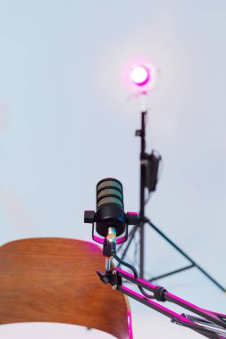 Podcast röportajı için kürsüye bir mikrofon yerleştirildi. Renkli sahne ışıkları arka planı aydınlatıyor ve öğleden sonra geç saatlerde tartışma için çekici bir ortam yaratıyor..