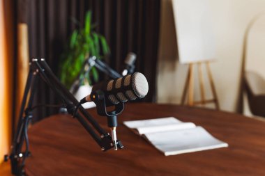 İyi donanımlı bir kayıt stüdyosunda kullanıma hazır yüksek kaliteli bir mikrofon bulunur. Notlar ahşap bir masanın üzerine konur. Bu da yaklaşan podcast tartışmasına hazırlık niteliğindedir..