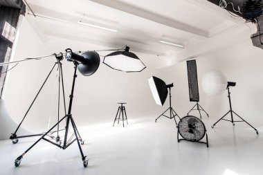 Parlak ışıklandırılmış siklonama stüdyosunda softbox ve standlar da dahil olmak üzere çeşitli ışıklandırma ekipmanları yer alıyor. Çeşitli fotoğraf seansları ve yaratıcı projeler için hazırlar..