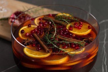 Portakal dilimleri, taze biberiye, nar tohumları ve tarçın çubuklarıyla dolu renkli bir punç kasesi Noel ve Şükran Günü kutlamaları için mükemmeldir..