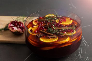 Büyük bir punç kasesinde canlı bir portakal, baharat ve biberiye karışımı sergilenir. Kutlama toplantıları için mükemmeldir. Etrafını saran malzemeler sıcak bir tatil ruhu getiriyor..