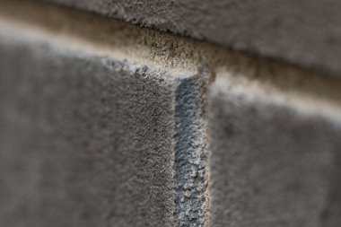 Gri beton blokların dokusu yüzey detaylarını ve eklem ayrımını göstermek için vurgulanmıştır. Odak maddenin pürüzlü ve renkli varyasyonlarını yakalar.