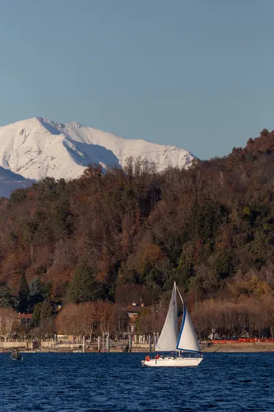 Gölde süzülen yelkenli Karlı Dağ Arkaplanına karşı