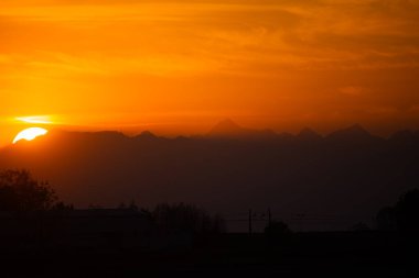 Parlak Turuncu Gökyüzü ile Dağ Aralığında Canlı Gün Batımı