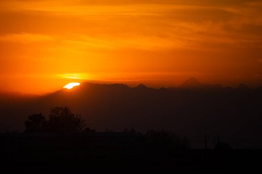 Canlı Turuncu Gökyüzü ile Dağ Siluetlerinin Üzerinde Huzurlu Gün Batımı