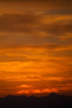 Çarpıcı Turuncu ve Sarı Gökyüzü ile Canlı Dağ Günbatımı