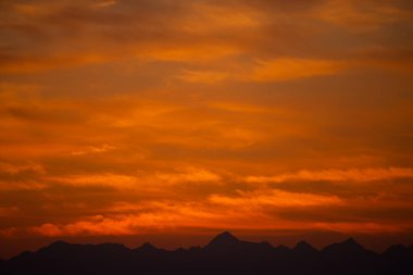 Canlı Turuncu Gökyüzü ile Dağ Siluetleri Üzerinde Manzaralı Gün Batımı