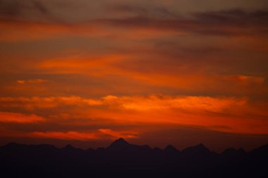 Canlı Kırmızı ve Turuncu Dağ Siluetleri Üzerindeki Görkemli Günbatımı
