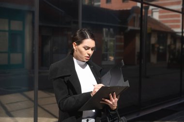 Genç kadın savunma avukatı ya da savcı müvekkili temsil ettiği mahkeme salonuna doğru yürürken davayı okuyup kontrol ediyor.. 