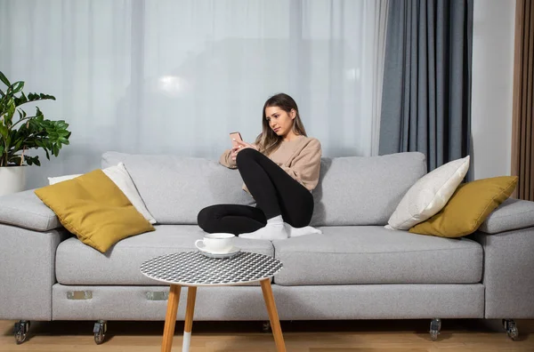 stock image Happy young woman caller talking on the phone at home, cheerful teen girl enjoys pleasant mobile conversation, smiling millennial female holding cell speaking making call by telephone in living room