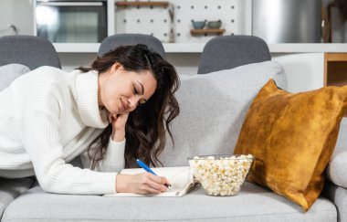 Yeni adımını ve satış ve çözümlerini geliştirmesini hatırlatmak için notlara iş fikirlerini yazan küçük bir şirketin genç bağımsız iş kadını. İş adamı evde çalışıyor..