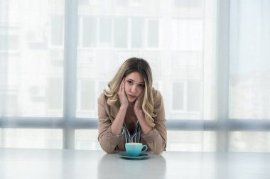 Ama önce kahve. Resmi görevdeki genç yorgun iş kadını ofiste boş bir masada kahve içerken giyiniyor. Beyaz yakalı kadın işçi, serbest çalışan mali uzman sabah rutini..