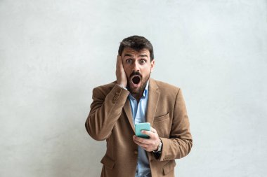 İyi ya da kötü haber. Şok olmuş iş adamının portresi telefona bakıyor korkunç mesajlar görüyor, sinirsel tepkiler veriyor. Resmi giyimde iş adamlarına göre fiyatlar yüksek, yüz ifadesi şoke edici