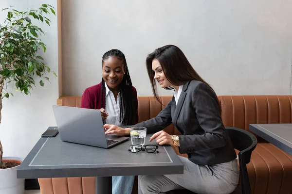 stock image Two young successful women friends and business partners monitor the statistics of their business on a laptop computer and the jump in the value of their small company shares on the stock market.