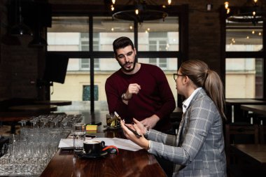 Bir restoranda oturan sağlık müfettişi, mutfakta kötü hijyen koşulları bulduktan sonra kafeterya sahibine ya da yöneticisine ceza ve olumsuz bir rapor yazar. Sağlık denetimi. 