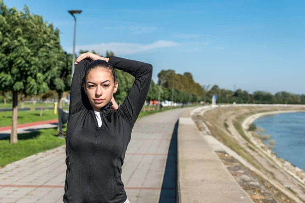 Young self loved teenage girl fitness exercises outdoor as morning routine for self-awareness of healthy life. Good posture woman stretching her muscles before workout training.