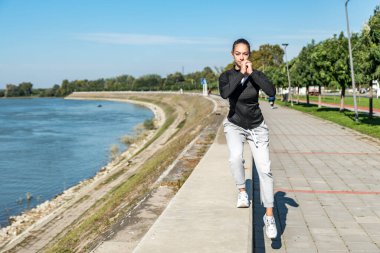 Genç kendini beğenmiş genç kız fitness egzersizleri sağlıklı yaşamın farkındalığı için sabah rutini olarak açık havada yapılır. Antrenmandan önce kaslarını esneten iyi bir kadın..