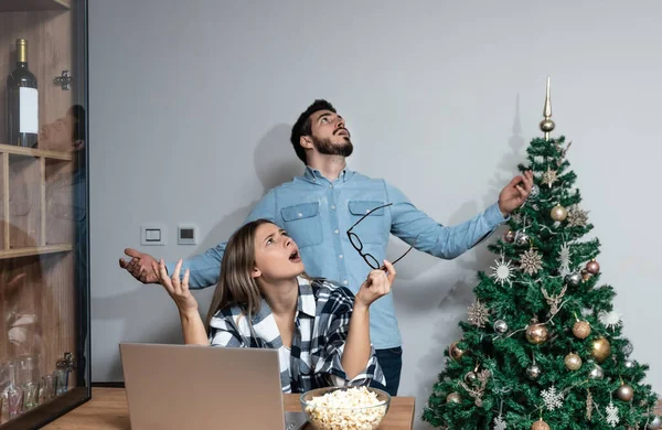 stock image Young couple stares at the ceiling and yells because a neighbor upstairs is having a party with loud music or renovating an apartment and workers are drilling with heavy tools. Noise pollution concept