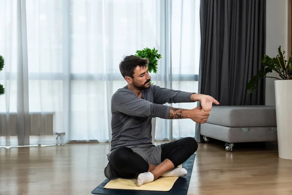 Young man cancer survivor practicing home workout yoga training, stretching muscles and breathing exercise for healthy life after long struggle with sickness and pain. Warmup exercises for meditation.