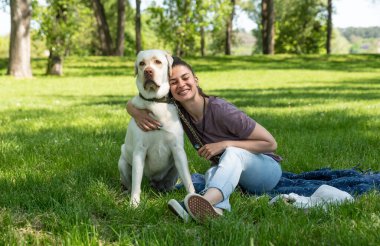 Young woman adopt young dog Labrador Retriever from animal rescue shelter center and gave him love and friendship. Female animal lover spending time with her puppy in the park.