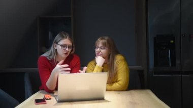 Two business women colleagues owners of small business and online e-commerce company talking live and looking at statistics on laptop computer have new ideas and solutions