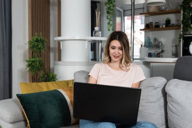 Young business woman home interior designer working on her laptop for new client who bought apartment and want improvement. Female Feng Shui expert looking on her computer design of furniture