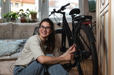 Young beautiful responsible environmental activist woman is repairing and preparing her bike for spring and summer because she doesn't want to pollute the air