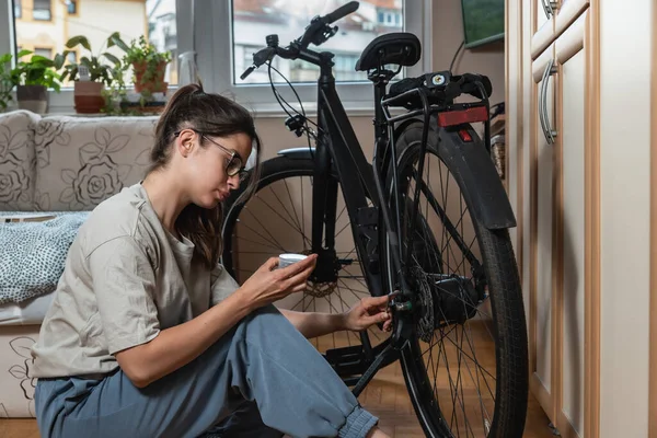 Young beautiful responsible environmental activist woman is repairing and preparing her bike for spring and summer because she doesn\'t want to pollute the air