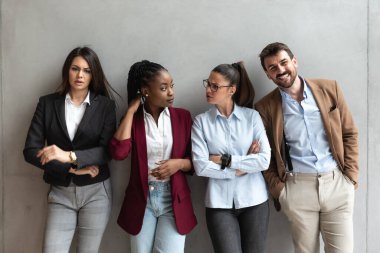 Group of young business people colleagues freelancers experts leaders of different professions in a company of marketing and financial experts standing leaning against wall with different attitude