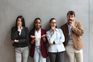 Group of young business people colleagues freelancers experts leaders of different professions in a company of marketing and financial experts standing leaning against wall with different attitude